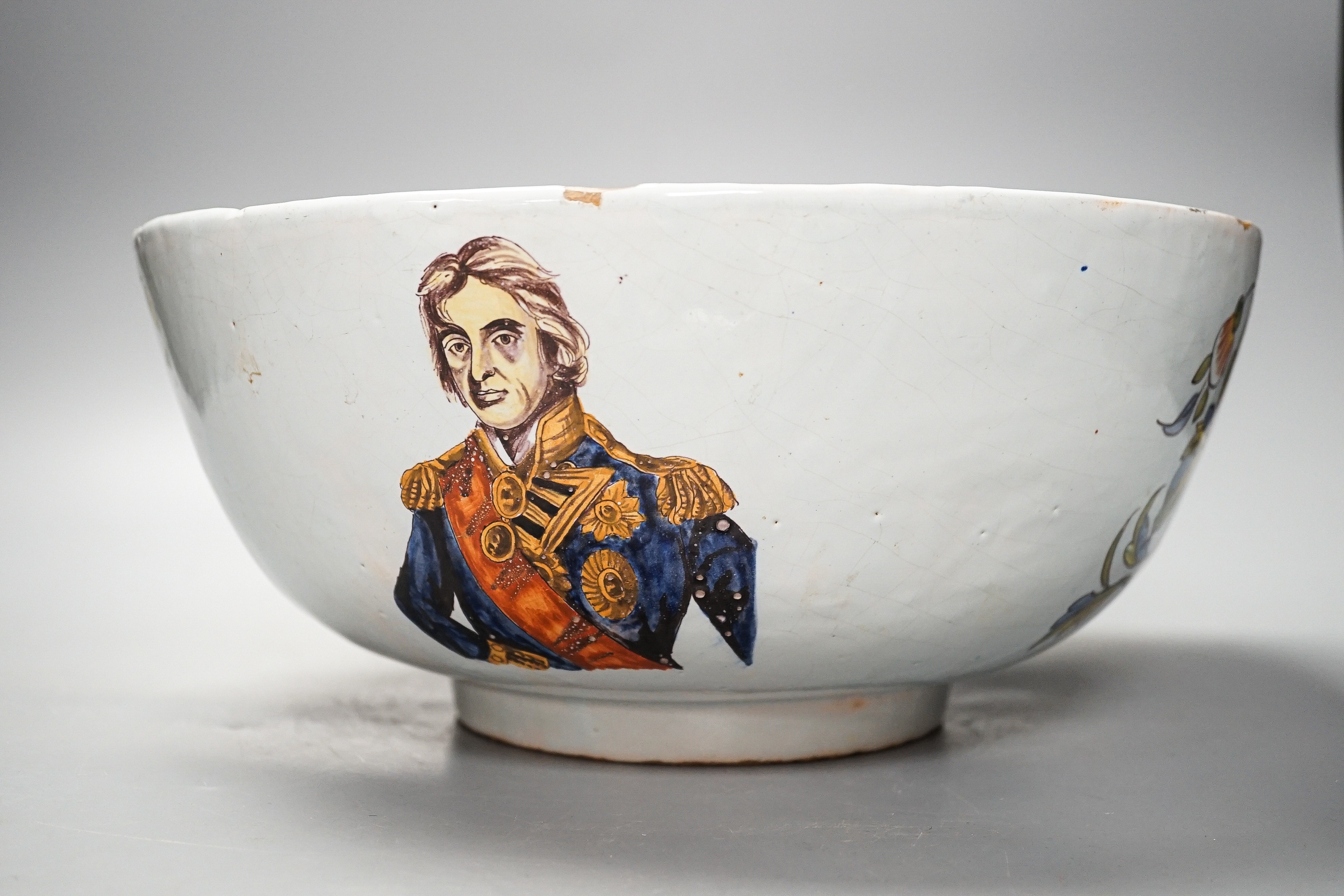 Lord Admiral Nelson. A commemorative Delftware punch bowl, 19th century, painted in polychrome with a portrait of Nelson, as hip and floral sprays, D. 30cm, splinter chip to edge